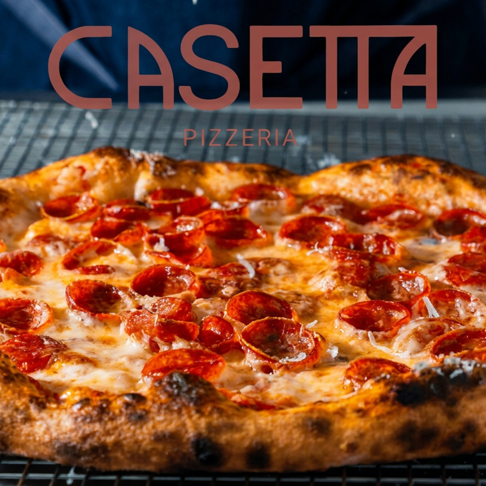 Pepperoni pizza with melted cheese and a charred crust cooling on a wire rack beneath Casetta Pizzeria branding.